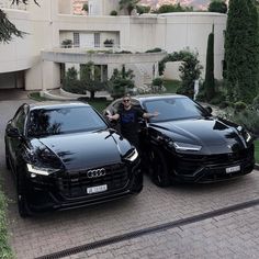 two black sports cars parked next to each other in front of a large white building