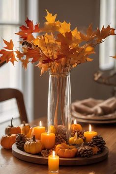 a vase filled with candles sitting on top of a wooden table covered in fall leaves