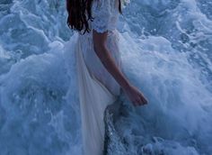 a woman is standing in the ocean waves