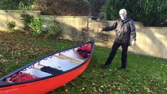 a man standing next to a red canoe