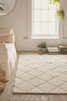 a living room area with a white rug and plants on the floor next to a window