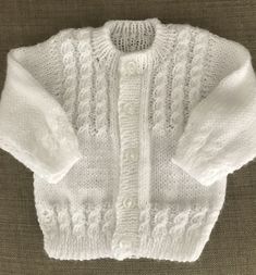 a white knitted sweater sitting on top of a couch