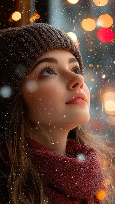 a woman wearing a hat and scarf looking up at the sky with lights in the background