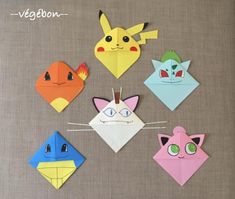 four different colored origami cats with eyes and ears on the top, one cat is