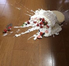 a cake that is on the floor with strawberries and whipped cream sprinkled all over it