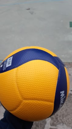 a close up of a person holding a large yellow and blue ball in their hand