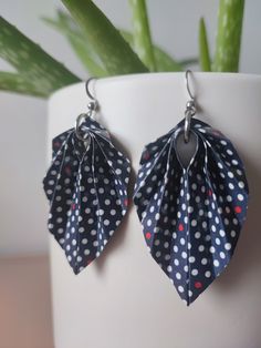 two pairs of blue and white polka dot paper leaves are hanging from silver earwires