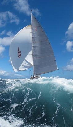 a sailboat is sailing through the ocean on a sunny day with blue skies and white clouds