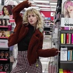 a woman with blonde hair is standing in front of a book shelf and pointing at something