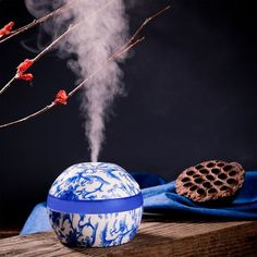 a blue and white vase with steam rising from it next to a cookie on a table