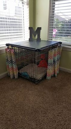 a dog cage in front of a window with the letter m on it's side