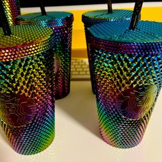 two colorful cups sitting on top of a table next to each other with straws sticking out of them