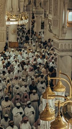 a large group of people standing around each other in front of a building with gold fixtures