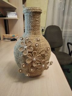 a crocheted vase sitting on top of a table next to an office chair