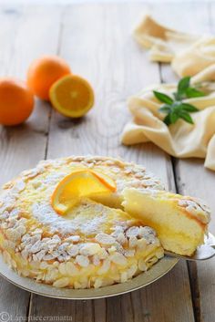 a cake with oranges and powdered sugar on the top sits on a plate