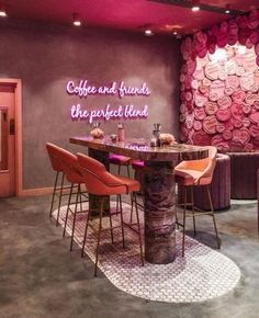 the interior of a restaurant with purple walls and pink chairs around a round wooden table