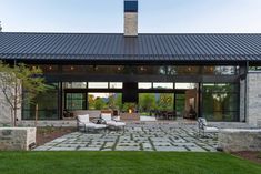 a patio with chairs and tables in front of a large glass door that leads to an outdoor living area