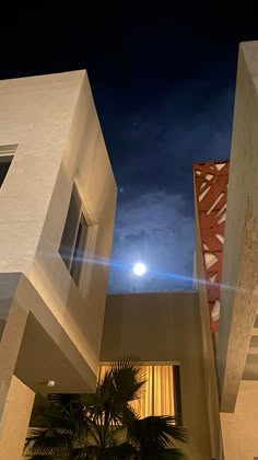 an apartment building with the moon in the sky and palm tree on the sidewalk next to it