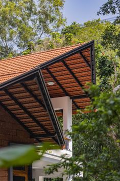 the roof of a house with trees in the back ground and bushes to the side