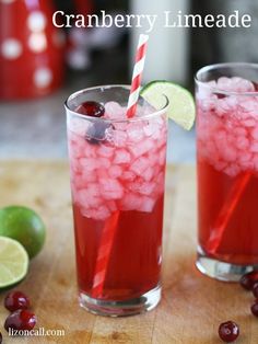 two glasses filled with cranberry limeade sitting on top of a wooden cutting board