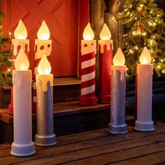 lighted candles are sitting in front of a red door with christmas decorations on the outside