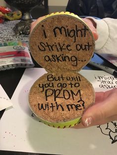 someone is holding up two corks with writing on them that read, i might shift out asking but can you go prom with me?