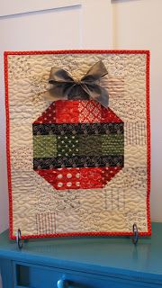 a quilted christmas ornament on top of a blue dresser with a bow