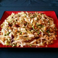 a red plate topped with coleslaw slaw covered in nuts and other toppings