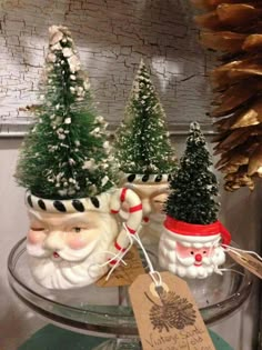 three small christmas trees in pots with santa's faces on them and a price tag hanging from the top