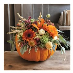 a pumpkin filled with flowers on top of a wooden table