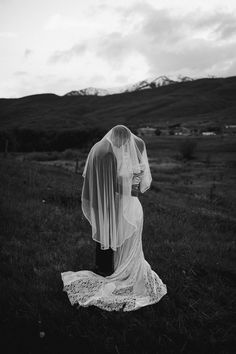 black and white photograph of a bride in the field with her veil draped over her head