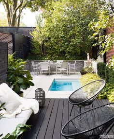 a small backyard with a pool surrounded by greenery