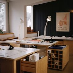 an office with many desks and drawers in front of a large window that has a lamp on top of it