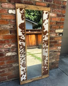 a cow print mirror sitting on top of a brick wall next to a door way