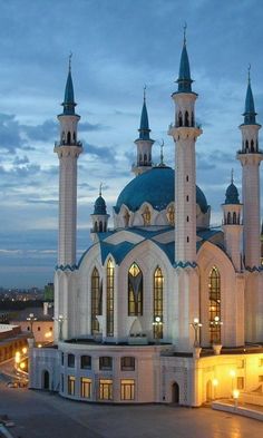 a large white building with blue domes and lights on it's sides at night