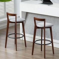 two stools in front of a desk with a laptop on it