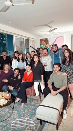 a group of people posing for a photo in a living room with a large window