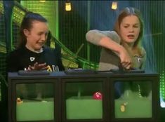 two children are playing with an object on the television show's set while one child looks at it