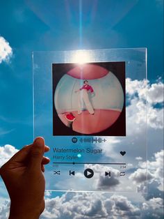 a person holding up a clear photo with the sky in the background