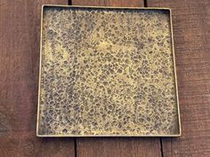 a square metal plate sitting on top of a wooden table