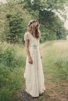 a woman wearing a white dress standing in the grass