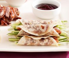 three burritos on a white plate with dipping sauce