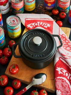 tomatoes and canned food on a cutting board next to an iron skillet with lid