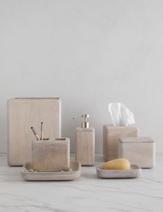 bathroom accessories including soap dispenser, toothbrush holder and soap dish on marble countertop