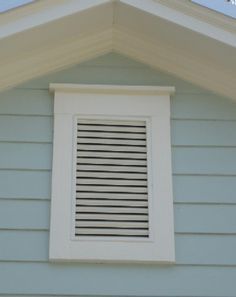 a small window on the side of a blue house with white trim and shutters