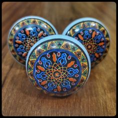 three decorative glass knobs sitting on top of a wooden table