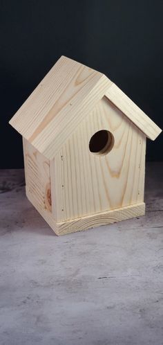 a wooden birdhouse sitting on top of a cement floor