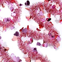 pink tinseled heart garlands on white background with hearts scattered all over them