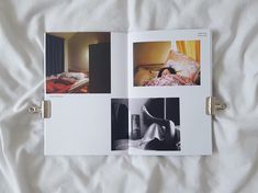 an open book with pictures on it laying on top of a white bed spread in front of a window