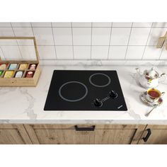 a black stove top sitting on top of a kitchen counter next to a tea pot